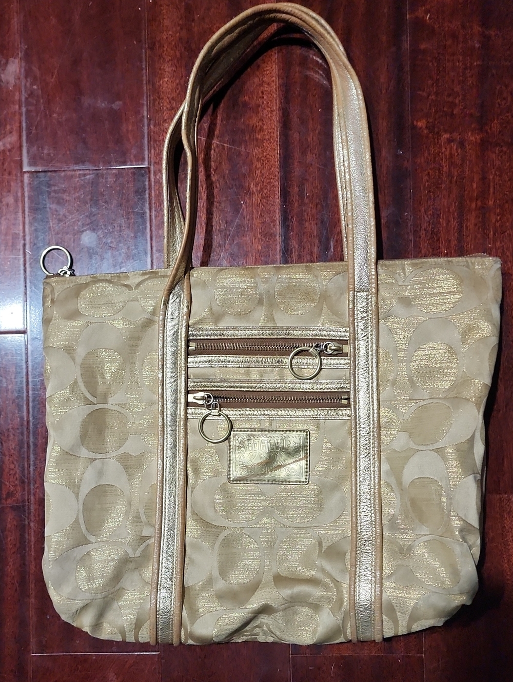 Coach Poppy Op Art Glam tote bag featuring a gold monogram jacquard design.